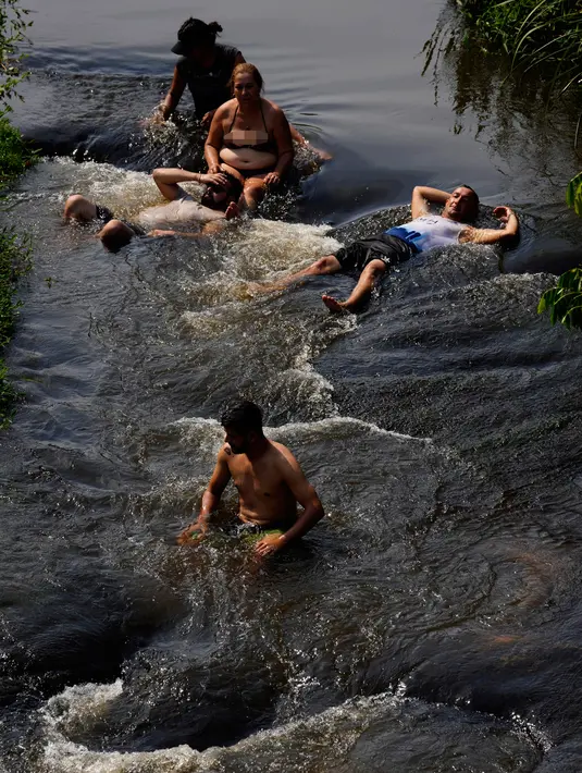 Orang-orang menyejukkan diri dari cuaca yang sangat terik di sungai saat gelombang panas di Paraguari, Paraguay, Minggu (16/1/2022). Suhu Paraguay secara umum mencapai 41 derajat celsius. (AP Photo/Jorge Saenz)