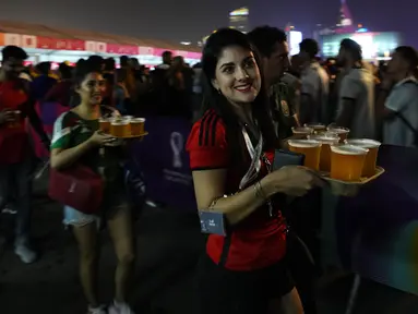 Suporter wanita membawa bir yang disediakan salah satu sponsor saat pembukaan FIFA Fan Festival Piala Dunia 2022 di Al Bidda Park, Doha, Minggu (20/11/2022). (AP Photo/Petr David Josek)