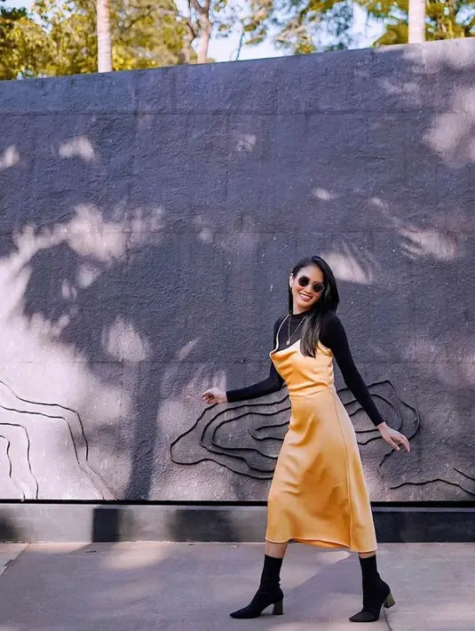 Tampil lebih stylish dengan padu padan inner panjang warna hitam dan silk dress warna mustard. Agar makin kece, coba tambahkan sepatu boots warna hitam seperti bintang Badarawuhi KKN Desa Penari ini. (Instagram/owliasarah).