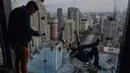 Seorang pengunjung berpose di Sampa Sky Observation Deck di Sao Paulo, Brasil pada 05 Agustus 2021. Gedung tersebut terinspirasi dari Skydeck Chicago di Amerika Serikat yang memiliki tinggi 103 lantai. (NELSON ALMEIDA / AFP)