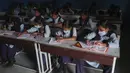 Sejumlah siswa mengenakan masker saat prose belajar mengajar di sebuah sekolah pemerintah di Hyderabad, India, Rabu (4/3/2020). (AP Photo/Mahesh Kumar A.)