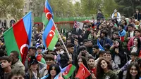 Rakyat Azerbaijan mengibarkan bendera nasional di Baku, Azerbaijan, Selasa (10/11/2020). Armenia dan Azerbaijan mengumumkan perjanjian damai untuk menghentikan pertempuran atas wilayah Nagorno-Karabakh di Azerbaijan berdasarkan pakta yang ditandatangani dengan Rusia. (AP Photo)