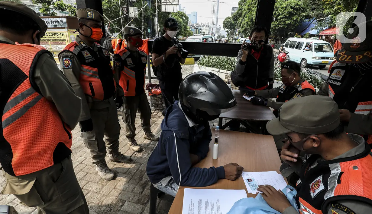 Petugas mendata warga pelanggar Pembatasan Sosial Berskala Besar (PSBB) yang terjaring razia masker di wilayah Tanah Abang, Jakarta, Senin (14/9/2020). Razia tersebut guna menekan kasus penyebaran COVID-19 di Jakarta pada masa PSBB. (Liputan6.com/Johan Tallo)