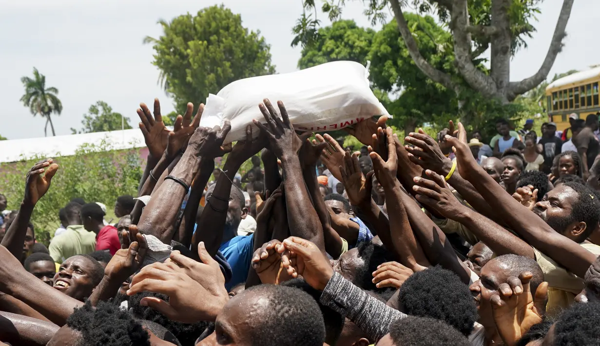 Warga berebut sekantong beras yang disumbangkan di dekat sebuah truk yang penuh dengan persediaan bantuan di Vye Terre, Haiti, Jumat (20/8/2021).  Bantuan swasta dan kiriman dari pemerintah AS dan lainnya tiba di semenanjung barat daya negara itu. dilanda. (AP Photo/Fernando Llano)