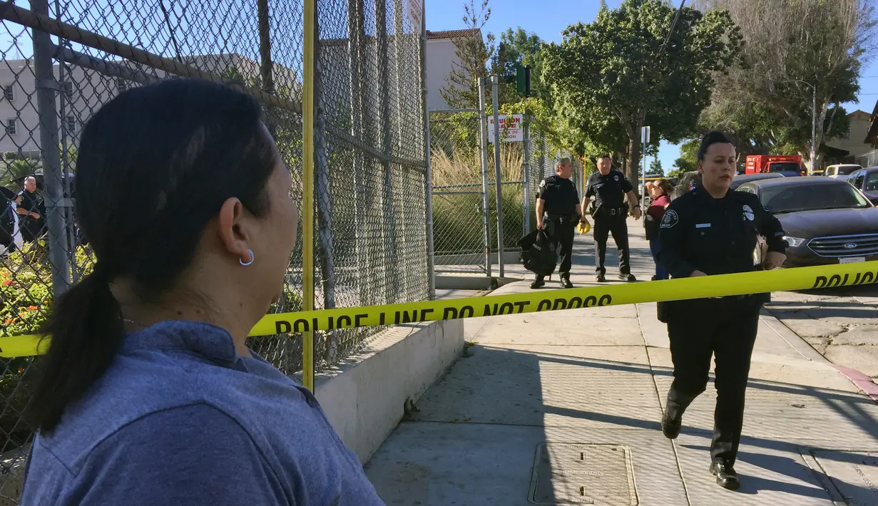 Warga melihat polisi menutup akses jalan menuju lokasi penembakan di sekolah menengah Salvador Castro, Los Angeles, Kamis (1/2). Lima orang terluka, satu di antaranya siswa berusia 15 tahun kritis karena tertembak bagian kepalanya. (AP/Damian Dovarganes)