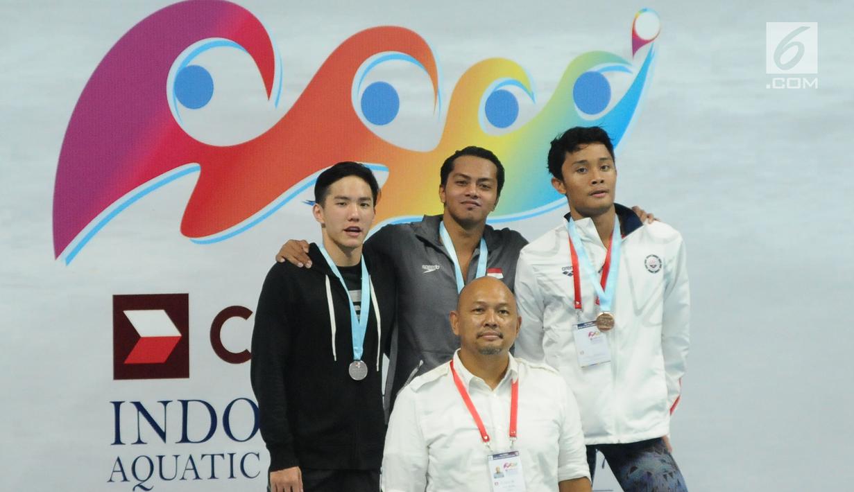 Perenang klub MNA, I Gede Siman Sudartawa (tengah) di podium kemenangan gaya punggung 100 m putra Kejuaraan Akuatik Indonesia Open 2017 di Stadion Aquatik GBK, Jakarta, Minggu (10/12). Siman menorehkan waktu 56,19 detik. (Liputan6.com/Helmi Fithriansyah)