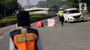 Petugas polisi mengarahkan kendaraan berplat nomor genap di pos penyekatan ganjil-genap di Bundaran Senayan, Minggu (5/9/2021). Pembatasan kendaraan dengan sistem pelat nomor kendaraan ini tetap berlaku di akhir pekan, Sabtu dan Minggu. (Liputan6.com/Angga Yuniar)
