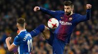 Pemain Barcelona, Gerard Pique berebut bola dengan pemain Espanyol, Leo Baptistao pada laga leg kedua perempat final Copa del Rey di Camp Nou, Kamis (25/1). Tiket semifinal berhasil diraih Barcelona usai mengalahkan Espanyol 2-0. (AFP PHOTO/LLUIS GENE)