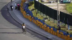 Seorang pria mengendarai sepeda dengan anak laki-laki, saat tabung gas kosong terlihat ditempatkan dalam antrian di Stadion Kriket Internasional Galle di Galle, Sri Lanka, Selasa (28/6/2022). Selain persoalan gas dan BBM, masyarakat juga dihadapkan dengan harga barang kebutuhan pokok yang semakin mahal akibat nilai inflasi yang terus meningkat. (AP Photo/Eranga Jayawardena)