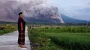 Seorang pria melihat saat Gunung Semeru mengeluarkan material vulkanik saat meletus, Lumajang, Jawa Timur, Indonesia, Minggu (4/12/2022). Gunung Semeru erupsi pada dini hari tadi sekitar pukul 02.46 WIB. (AP Photo)
