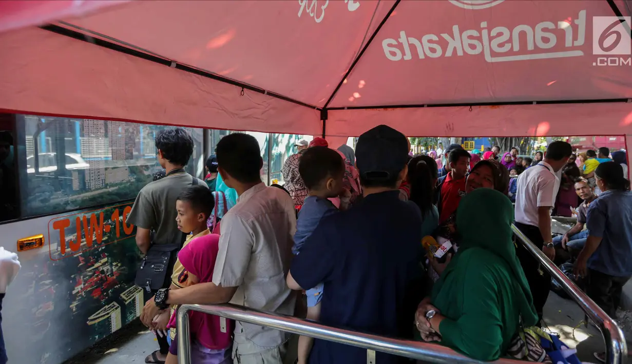 Warga berbaris mengantre untuk naik bus City Tour di kawasan Masjid Istiqlal, Jakarta, Senin (25/12). Sejumlah warga juga memanfaatkan fasilitas bus City Tour ini untuk berkeliling Jakarta bersama keluarga. (Liputan6.com/Faizal Fanani)