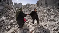 Warga Palestina berjalan melewati puing-puing rumah yang hancur di Khan Yunis, Jalur Gaza Selatan pada 6 Maret 2024. Kementerian Kesehatan Gaza juga mengungkap sebanyak 60 ribu wanita hamil di wilayah tersebut menderita kekurangan gizi dan dehidrasi akibat perang Israel. (Foto oleh AFP)