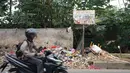 Pengendara melintasi tumpukan sampah rumah tangga di Jalan Raya Tanah Baru kawasan Depok, Jawa Barat, Rabu (15/5/2019). Kurangnya tempat penampungan membuat warga terpaksa membuang sampah di lokasi tersebut, meskipun menimbulkan bau tidak sedap serta mengotori jalan. (Liputan6.com/Immanuel Antonius)