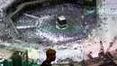 Perwira polisi Arab Saudi berjalan melewati layar raksasa yang menampilkan Masjidil Haram di Pusat Pemantauan 911, Makkah, Selasa (6/8/2019). Pusat Pemantauan 911 siap menjawab penelepon di luar bahasa Arab. (AP Photo/Amr Nabil)