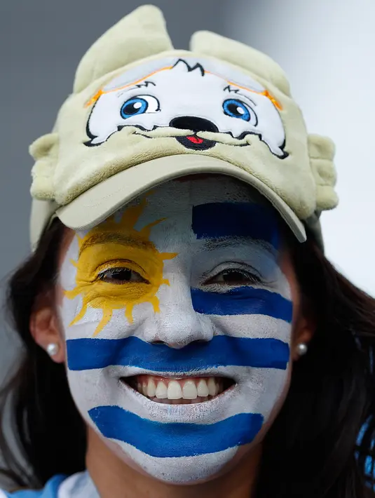 Seorang wanita mengecat wajahnya dengan bendera Uruguay jelang laga antara Uruguay dan Rusia dalam penyisihan Grup A Piala Dunia 2018 di Samara Arena, Samara, Rusia, Senin (25/6). (AP Photo/Hassan Ammar)