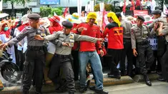 Personel kepolisian berusaha menahan para bidan desa yang berupaya menutup akses jalan saat demonstrasi di depan gedung Kemenkes, Jakarta, Rabu (4/5). Para bidan menuntut diangkat menjadi pegawai tetap tanpa syarat.  (Liputan6.com/Yoppy Renato)