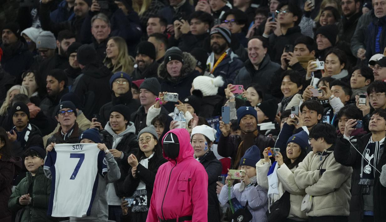 Seseorang berpakaian seperti penjaga Squid Games dengan berdiri di area penonton selama pertandingan lanjutan Liga Inggris 2024/2025 antara Tottenham Hotspur melawan Liverpool di Stadion Tottenham Hotspur, London, Inggris Minggu (22/12/2024). Seperti diketahui, aksi tersebut ternyata merupakan promo musim kedua serial Korea Selatan tersebut. (AP Photo/Dave Shopland)