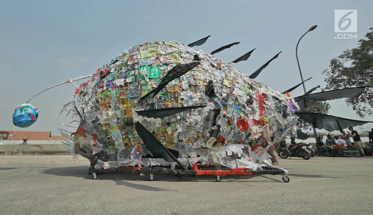 Aktivis pemerhati lingkungan mengarak monster plastik saat aksi Tolak Penggunaan Plastik Sekali Pakai di Pelabuhan Sunda Kelapa, Jakarta, Sabtu (20/7/2019). Monster plastik itu berupa rangka berbentuk ikan jenis anglerfish yang ukurannya sebesar mobil sampah. (Liputan6.com/Herman Zakharia)