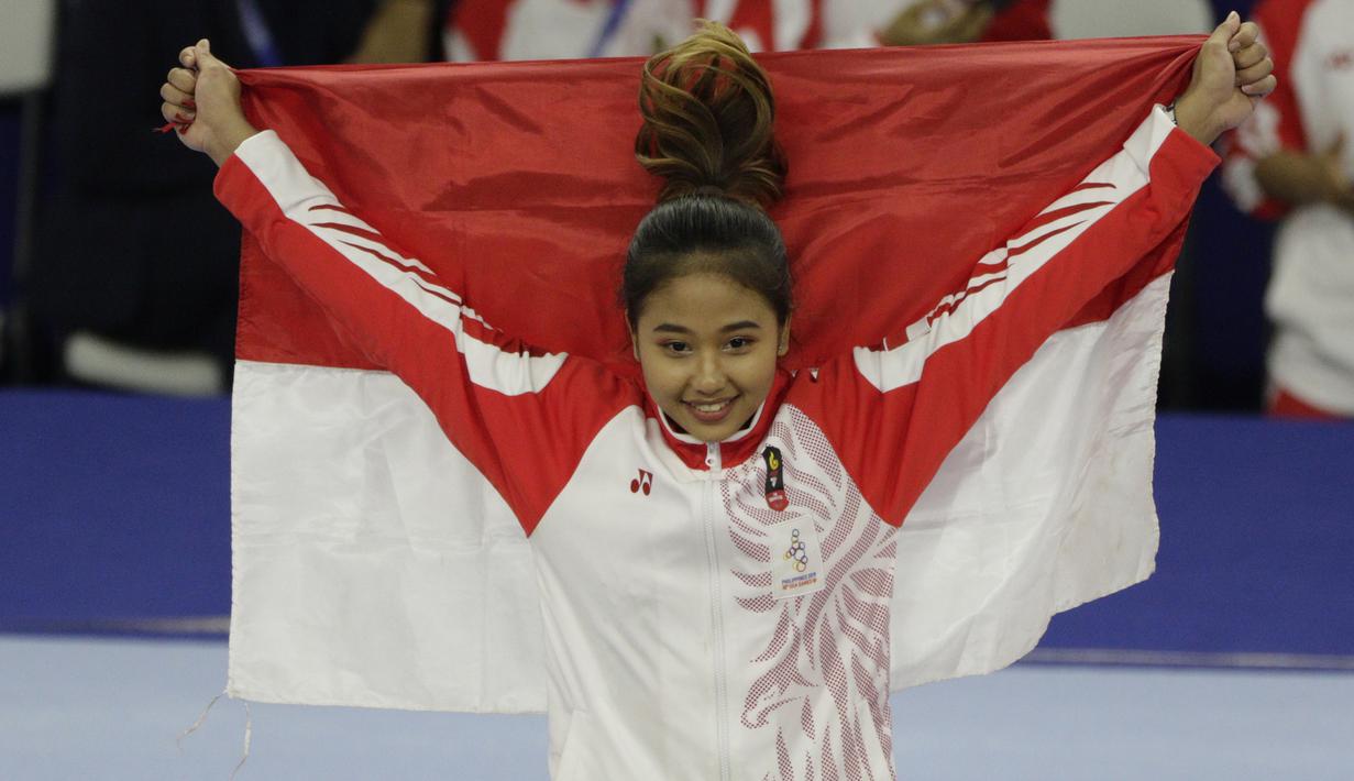 Pesenam Indonesia, Rifda Irfanaluthfi, berpose dengan bendera usai bertanding pada SEA Games 2019 di Kompleks Rizal Memorial, Manila, Senin (2/12). Dirinya berhasil meraih medali perak dari nomor all-round individual putri cabang senam. (Bola.com/M Iqbal