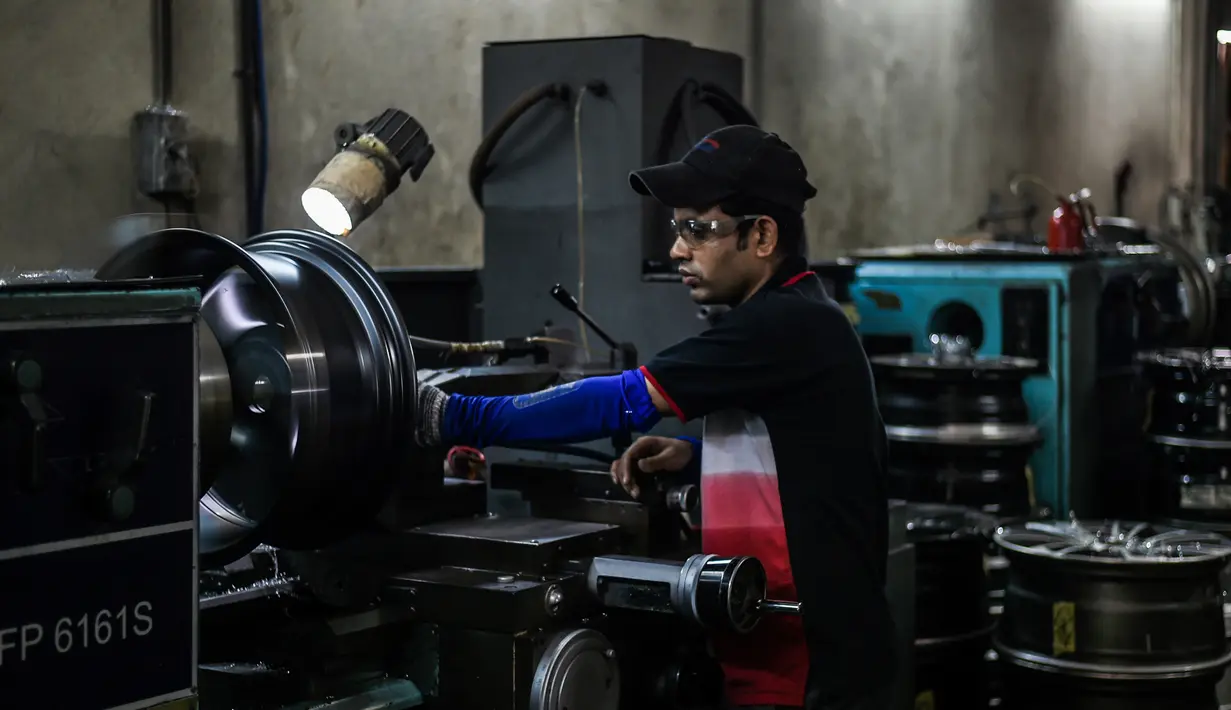 Seorang pekerja menggunakan mesin untuk memotong roda alloy di sebuah bengkel di Ampang, di pinggiran kota Kuala Lumpur, Malaysia (18/7). (AFP Photo/Mohd Rasfan)