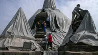 Relawan melepaskan penutup pelindung dari stupa candi Borobudur di Magelang, provinsi Jawa Tengah pada 17 Februari 2014 untuk memulai pembersihan endapan abu vulkanik menyusul letusan gunung berapi Gunung Kelud. (AFP Photo/Suryo Wibowo)