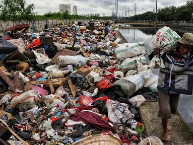 Warga membawa sampah sisa banjir yang dikumpulkan dari sepanjang Kali Cengkareng, Jakarta Barat, Kamis (9/1/2020). Tumpukan sampah di sepanjang bantaran kali dan rumah-rumah warga terlihat setelah banjir yang melanda sejumlah kawasan Jakarta mulai surut. (Liputan6.com/Johan Tallo)