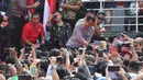 Presiden Joko Widodo menyalami warga yang berkerumun menyaksikan peresmian pengoperasian Moda Raya Terpadu Jakarta fase 1 di Kawasan Bundaran HI, Jakarta, Minggu (24/3). Acara ini sekaligus pencanangan pembangunan Moda Raya Terpadu Jakarta fase 2. (Liputan6.com/Helmi Fithriansyah)