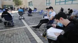 Para murid sekolah menengah atas (SMA) belajar di area luar ruangan sebuah sekolah di Kota Modiin, Israel pada  29 November 2020. Israel memulai kembali kegiatan pembelajaran tatap muka untuk SMA di kota besar dan kecil yang dikategorikan sebagai zona "hijau" atau "kuning". (Xinhua/Gil Cohen Magen)