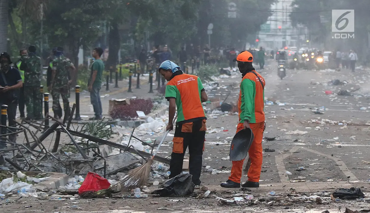 Petugas Penanganan Prasarana dan Sarana Umum (PPSU) atau Pasukan Oranye membersihkan sisa puing-puing pasca kerusuhan di kawasan Wahid Hasyim, Jakarta, Kamis (23/5/2019). Kerusuhan massa yang sebelumnya berdemo di depan gedung Bawaslu melebar ke Jalan Wahid Hasyim. (Liputan6.com/Herman Zakharia)