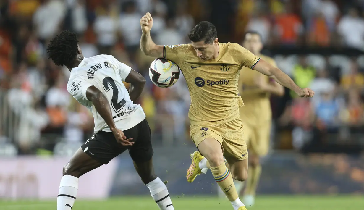 Bek Valencia Thierry Correia berebut bola dengan penyerang Barcelona Robert Lewandowski pada jornada ke-12 La Liga 2022/23 di Mestalla, Minggu (30/10/2022) dini hari WIB. Menghadapi tuan rumah Valencia, Barcelona berhasil menang dengan skor tipis 1-0. (AP Photo/Alberto Saiz)