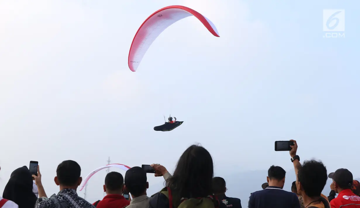 Salah satu atlet paralayang nomor cross country unjuk kebolehan saat latihan di kawasan Puncak, Cianjur, Jawa Barat, Kamis (26/7). Selain meninjau kesiapan venue, Menpora juga melihat latihan atlet paralayang Indonesia. (Liputan6.com/Helmi Fithriansyah)