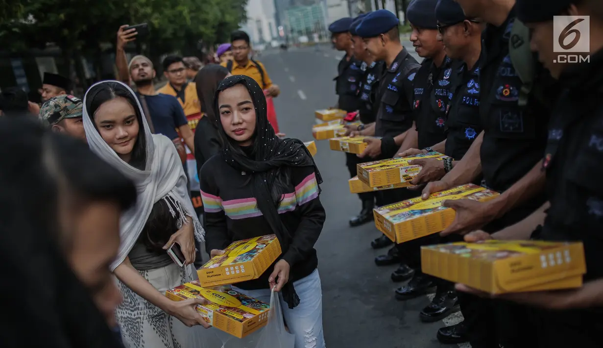 Peserta aksi yang tergabung dalam Mahasiswa dan Pemuda Relawan Cinta NKRI membagikan takjil ke anggota Polri yang bertugas di Gedung Bawaslu RI, Jakarta, Minggu (26/5). Aksi simpatik sebagai wujud apresiasi kepada anggota Polri-TNI yang menjaga keamanan aksi 22 Mei 2019. (Liputan6.com/Faizal Fanani)
