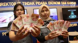 Dua petugas menunjukkan contoh barang bukti uang palsu di booth Direktorat Tindak Pidana Ekonomi dan Khusus saat berlangsungnya Bareskrim Polri Expo 2018 di Jakarta, Selasa (6/3). (Liputan6.com/Arya Manggala)