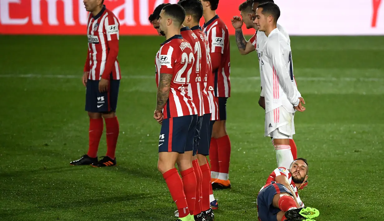 Gelandang Atletico Madrid, Koke berbaring di belakang rekan-rekannya yang membuat pagar hidup untuk menjaga tendangan bebas yang dilakukan pemain Real Madrid dalam laga lanjutan Liga Spanyol 2020/21 di Alfredo Di Stefano Stadium, Sabtu (12/12/2020). (AFP/Oscar Del Pozo)
