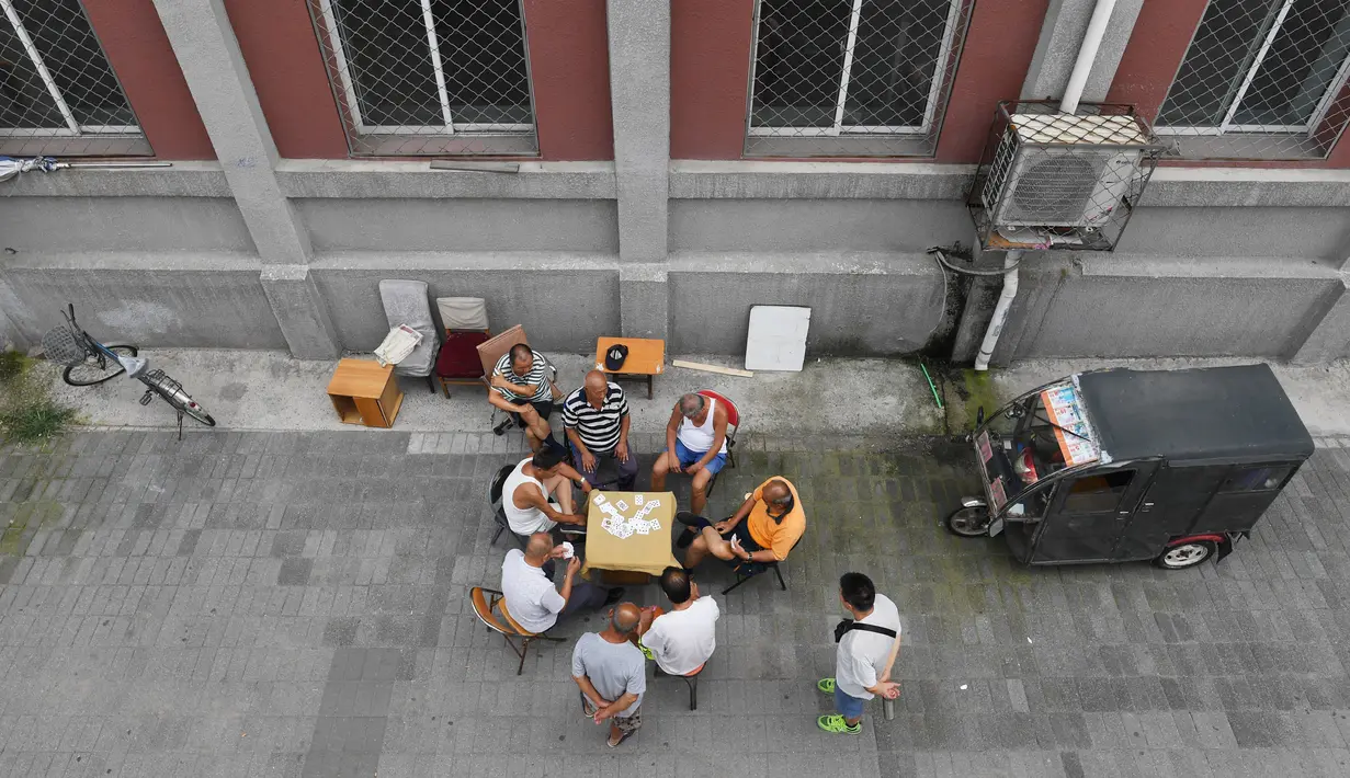 Suasana sekelompok pria bermain kartu di trotoar di luar gedung apartemen di Beijing, (10/8). Yang populer di banyak negara misalnya poker, canasta, blackjack, casino, solitaire, bridge, dengan jumlah pemain yang bisa berbeda-beda. (AFP Photo/Greg Baker)