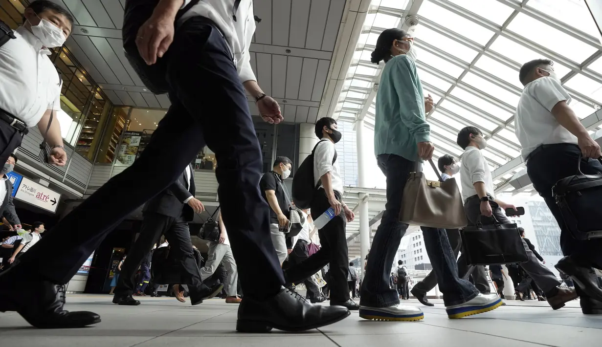 Komuter yang mengenakan masker berjalan di lorong selama jam sibuk di Stasiun Shinagawa, Tokyo, Senin (12/7/2021). Otoritas Jepang menempatkan Tokyo di bawah keadaan darurat Covid-19 keempat sebagai upaya menahan lonjakan kasus infeksi virus Corona dari Senin hingga 22 Agustus. (AP /Eugene Hoshiko)
