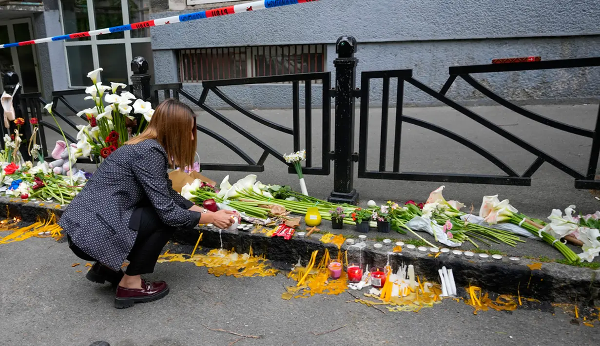 Ribuan orang berkumpul di lingkungan sekolah dasar itu pada malam hari untuk meletakkan bunga dan menyalakan lilin. (AP Photo/Darko Vojinovic)