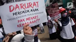 Massa Aliansi Kompak menujukkan poster tuntutan saat menggelar aksi di depan Kemenkes, Jakarta, Kamis (26/11/2020). Revisi Peraturan Pemerintah No. 109 Tahun 2012 (PP 109/2012) terkait pengamanan bahan yang mengandung zat adiktif berupa produk tembakau bagi kesehatan. (Liputan6.com/Herman Zakharia)