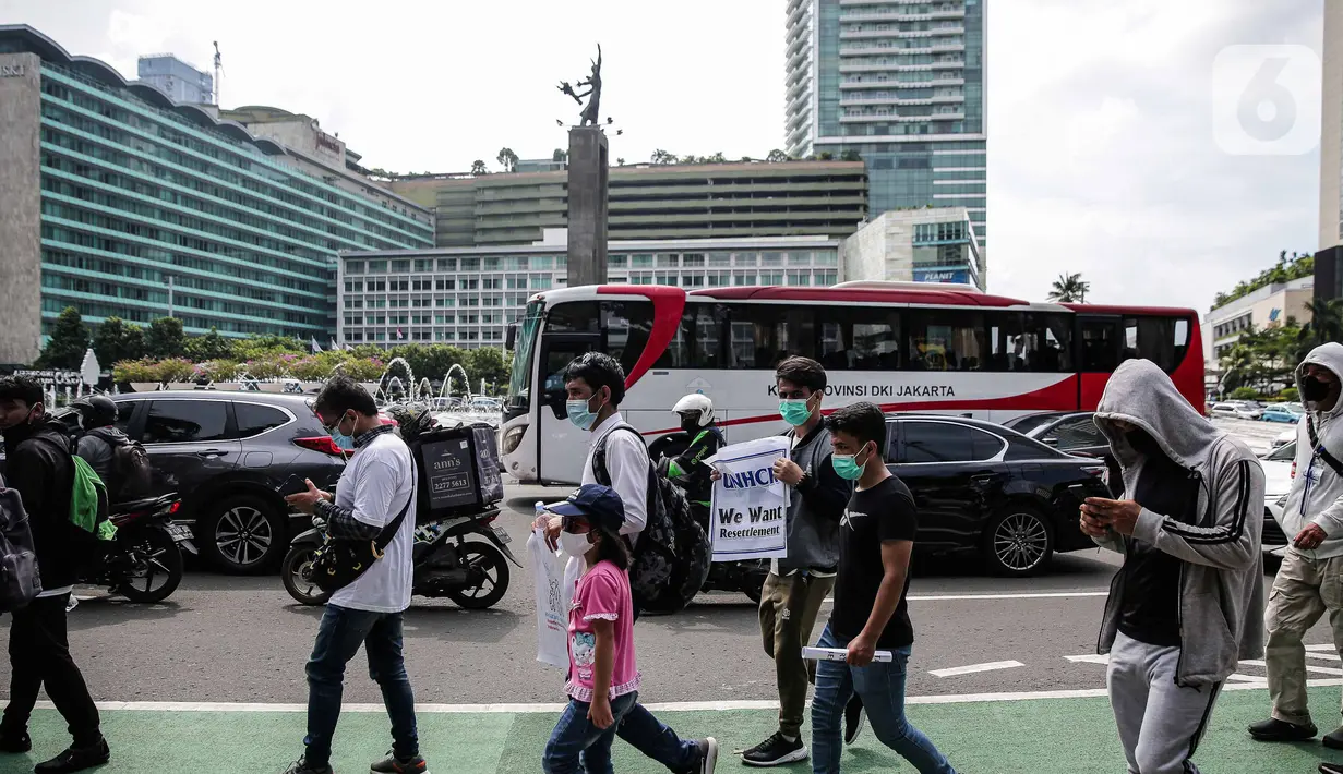 Ratusan imigran Afghanistan jalan kaki menuju Kedubes Kanada di Jakarta, Senin (13/12/2021). Dengan membawa spanduk dan poster, mereka menuntut UNHCR dan IOM segera memproses penempatan mereka ke negara tujuan seperti Kanada, Australia, Selandia Baru maupun AS. (Liputan6.com/Faizal Fanani)