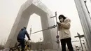 Seorang wanita berdiri di dekat menara CCTV ikonik saat badai pasir di Beijing (28/3/2021). Pada Senin (15/3/2021) pagi, langit Beijing menjadi jingga, membatasi jarak pandang hingga kurang dari 1.000 meter dan mengganggu lalu lintas. (AP Photo/Ng Han Guan)
