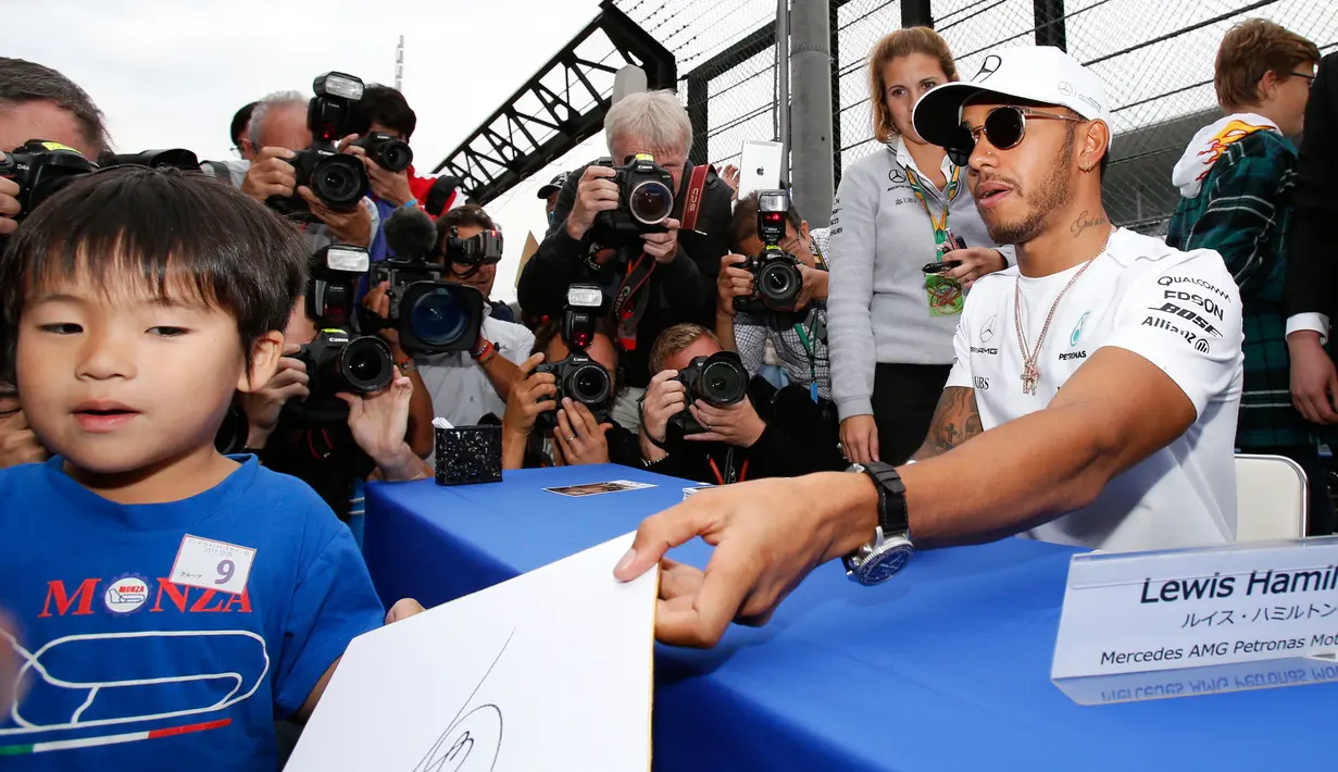 Pembalap Mercedes Lewis Hamilton memberi tanda tangan kepada seorang bocah Jepang jelang Grand Prix F1 di Sirkuit Suzuka, Jepang (5/10). Sebelum bertanding pada 8 Oktober mendatang, Hamilton menyapa penggemar di Jepang. (AP Photo/Toru Takahashi)