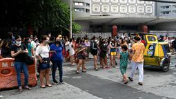 Warga menyelamatkan diri dengan keluar bangunan setelah gempa berkekuatan magnitudo 7,1 terasa di Manila, Filipina, Rabu (27/7/2022). Gempa mengguncang wilayah Dolores, Filipina. (JAM STA ROSA/AFP)