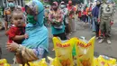 Seorang ibu membawa anaknya membeli minyak goreng kemasan saat operasi pasar minyak goreng murah di Kantor Kecamatan Pamulang, Tangerang Selatan, Selasa (11/1/20222). Minyak murah itu dijual dengan harga Rp14 ribu per liter dan hanya diperbolehkan membeli sebanyak 2 liter. (merdeka.com/Arie Basuki)