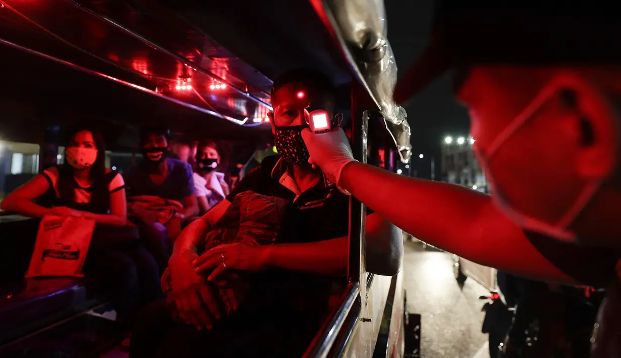 Polisi memeriksa suhu tubuh penumpang dalam jeepney di pos pemeriksaan virus corona COVID-19 di Manila, Filipina, Senin (16/3/2020). Polisi beserta petugas lalu lintas dan petugas desa melakukan pengecekan suhu tubuh warga untuk mencegah penyebaran virus corona COVID-19. (AP Photo/Aaron Favila)