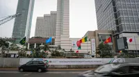 Sejumlah kendaraan melintasi deretan bendera negara peserta Konferensi Asia Afrika ke-60 yang terpasang di dinding proyek MRT kawasan Bundaran HI, Jakarta, Selasa (14/4/2015). (Liputan6.com/Faizal Fanani)