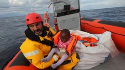 Oscar Camps, pendiri Spanyol LSM Proactiva Open Arms saat menyelamatkan seorang anak imigran di perahu yang penuh sesak di Laut Meditarania, sekitar 36 mil laut dari lepas pantai Libya (2/2). (Reuters/Yannis Behrakis)