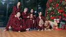 Erika Carlina bersama keluarga dan putranya tampil kompak mengenakan piyama motif tartan merah untuk foto Natal tahun 2025. [@eri.carl]