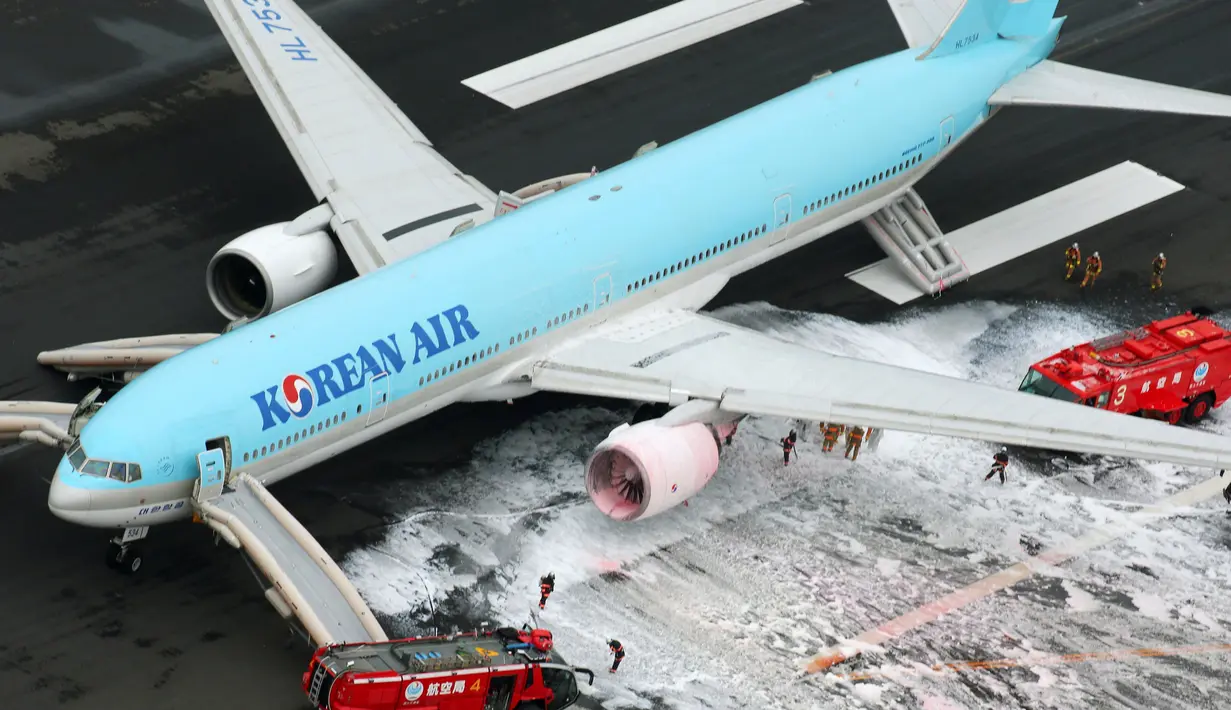 Gambar udara menunjukkan petugas pemadam kebakaran menyemprotkan busa pada mesin pesawat Korean Air Lines setelah asap keluar dari bagian mesin sebelah kiri itu di bandara Haneda di Tokyo, Jepang, (27/5). (Reuters/ Kyodo)