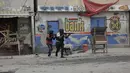 <p>Petugas polisi berlindung selama operasi anti-geng di lingkungan Portail, Port-au-Prince, sehari setelah massa di ibu kota Haiti itu menarik 13 tersangka anggota geng dari tahanan polisi lalu memukuli dan membakar mereka sampai mati. (AP Photo/Odelyn Joseph)</p>
