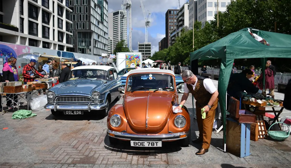 Pedagang memoles kap mesin VW Beatle di Classic Car Boot Sale, London, Inggris, 7 Agustus 2021. Classic Car Boot Sale berlangsung selama dua hari. (JUSTIN TALLIS/AFP)